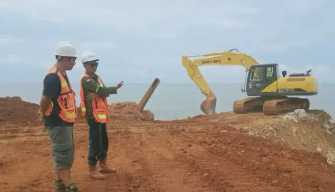 Two field personnel beside excavation equipment