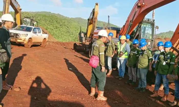 Site team gathered beside excavation equipment